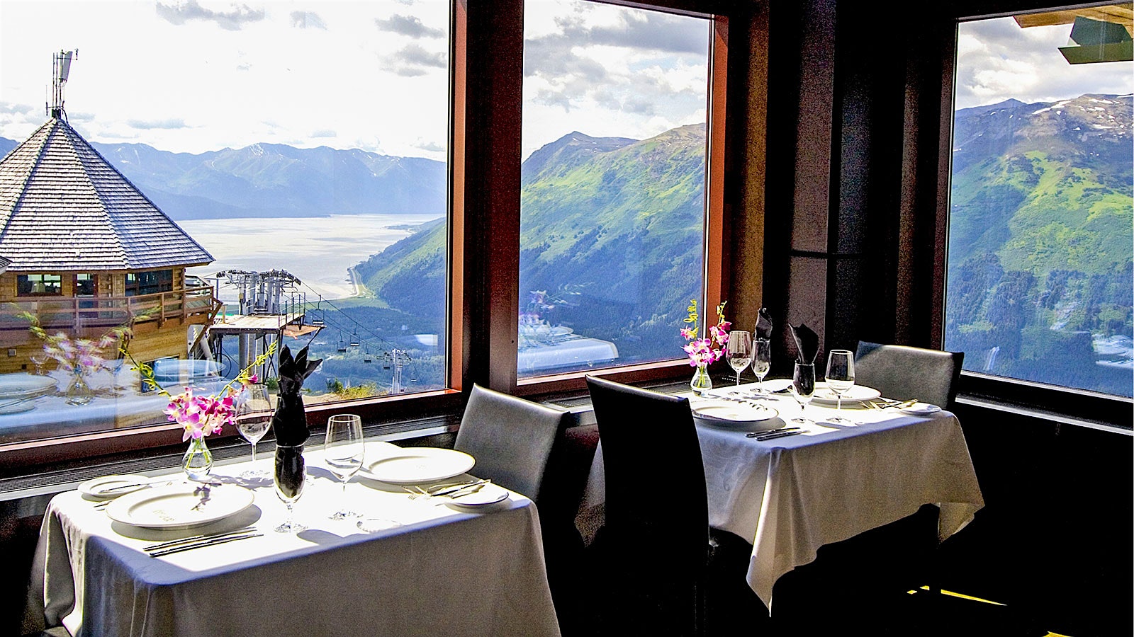 A table set with glasses and a bottle of wine at Seven Glaciers, with a window view of glaciers